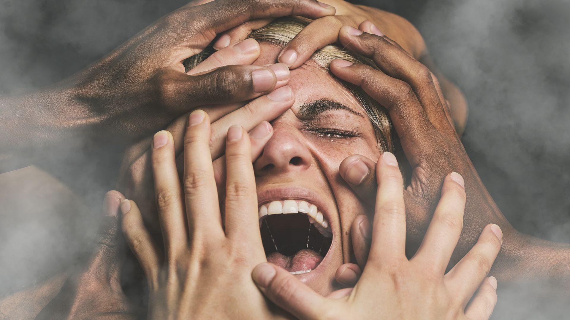 Emotional addiction: Depressed woman being grabbed by multiple hands with dark background
