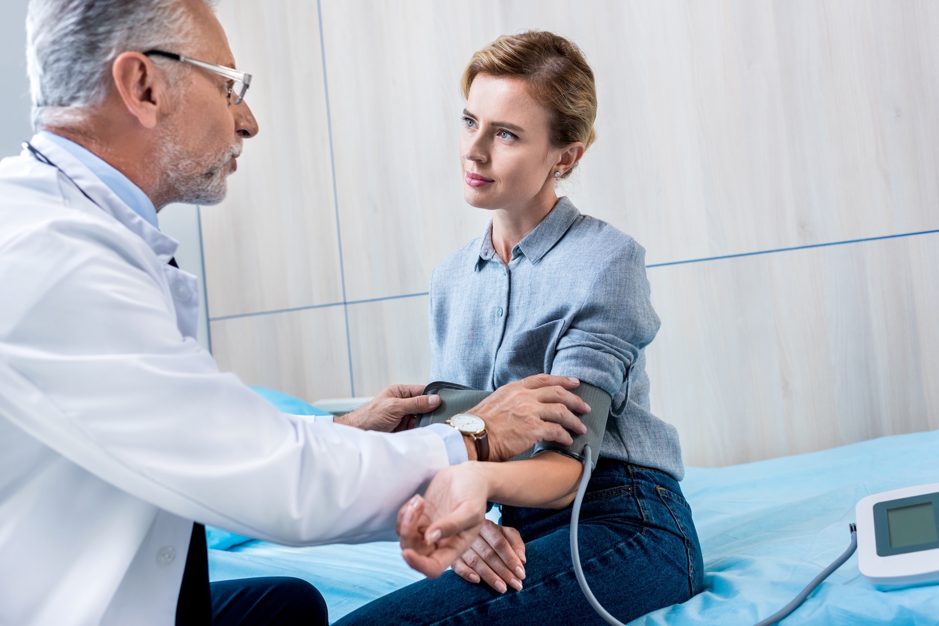 mature-male-doctor-measuring-pressure-of-female-patient-struggling-with-alcohol-addiction