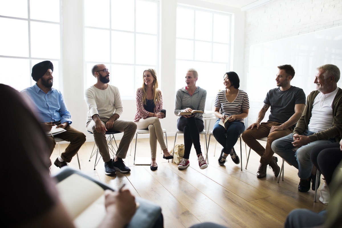 A group of people sitting in on a group therapy session. A group of people sitting in on a group therapy session.