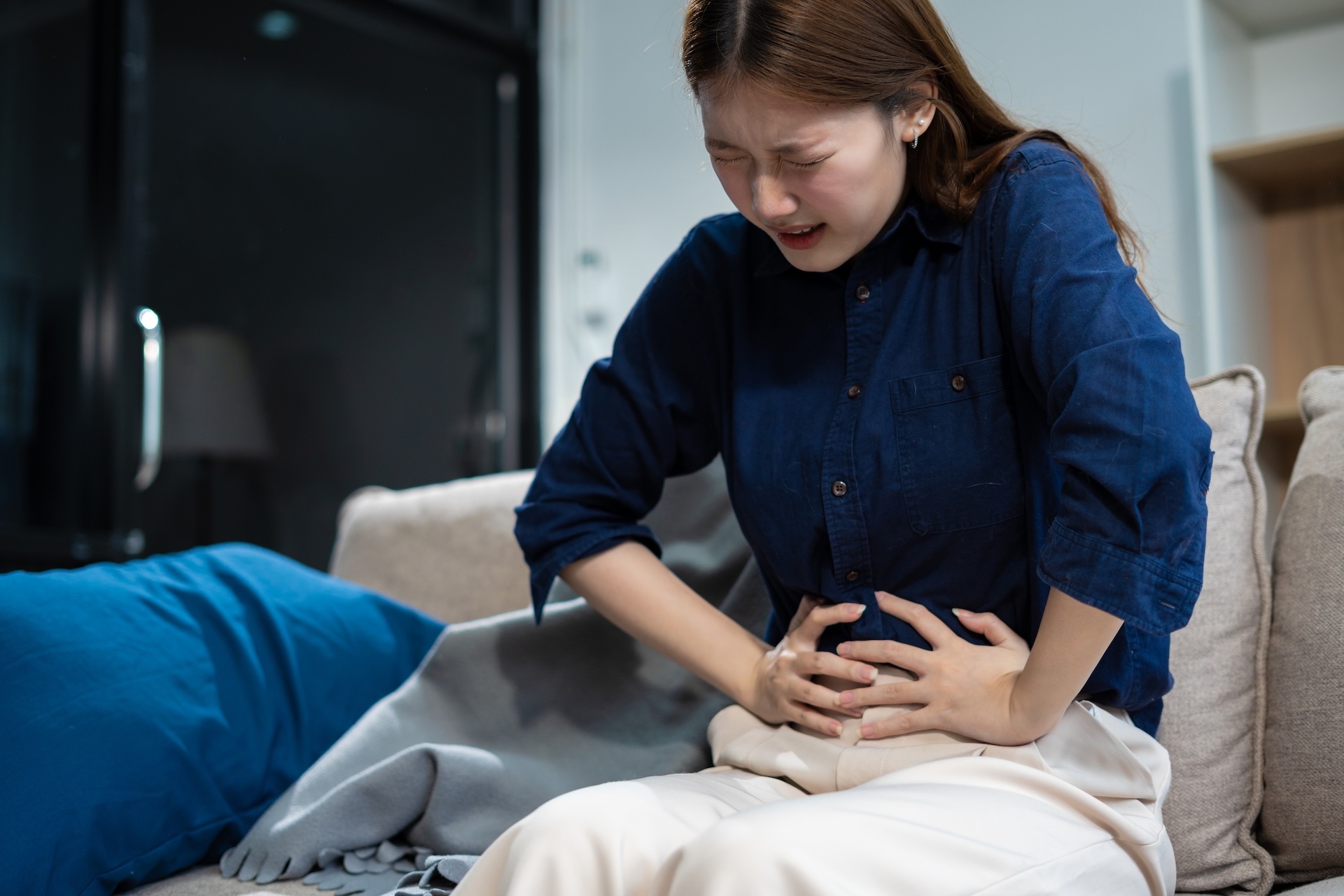Ibuprofen addiction victim holding her stomach in pain.
