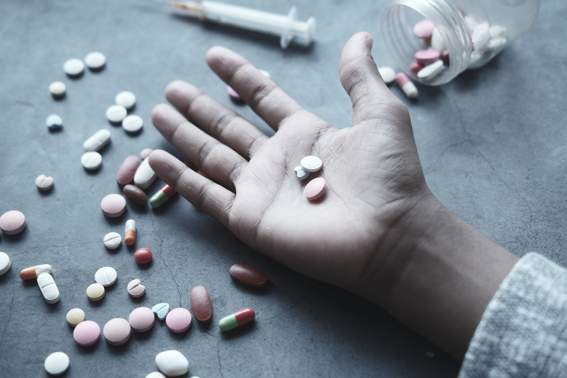 drug-abuse-concept-with-many-pills-on-hand-against-2023-11-27-05-08-12-utc