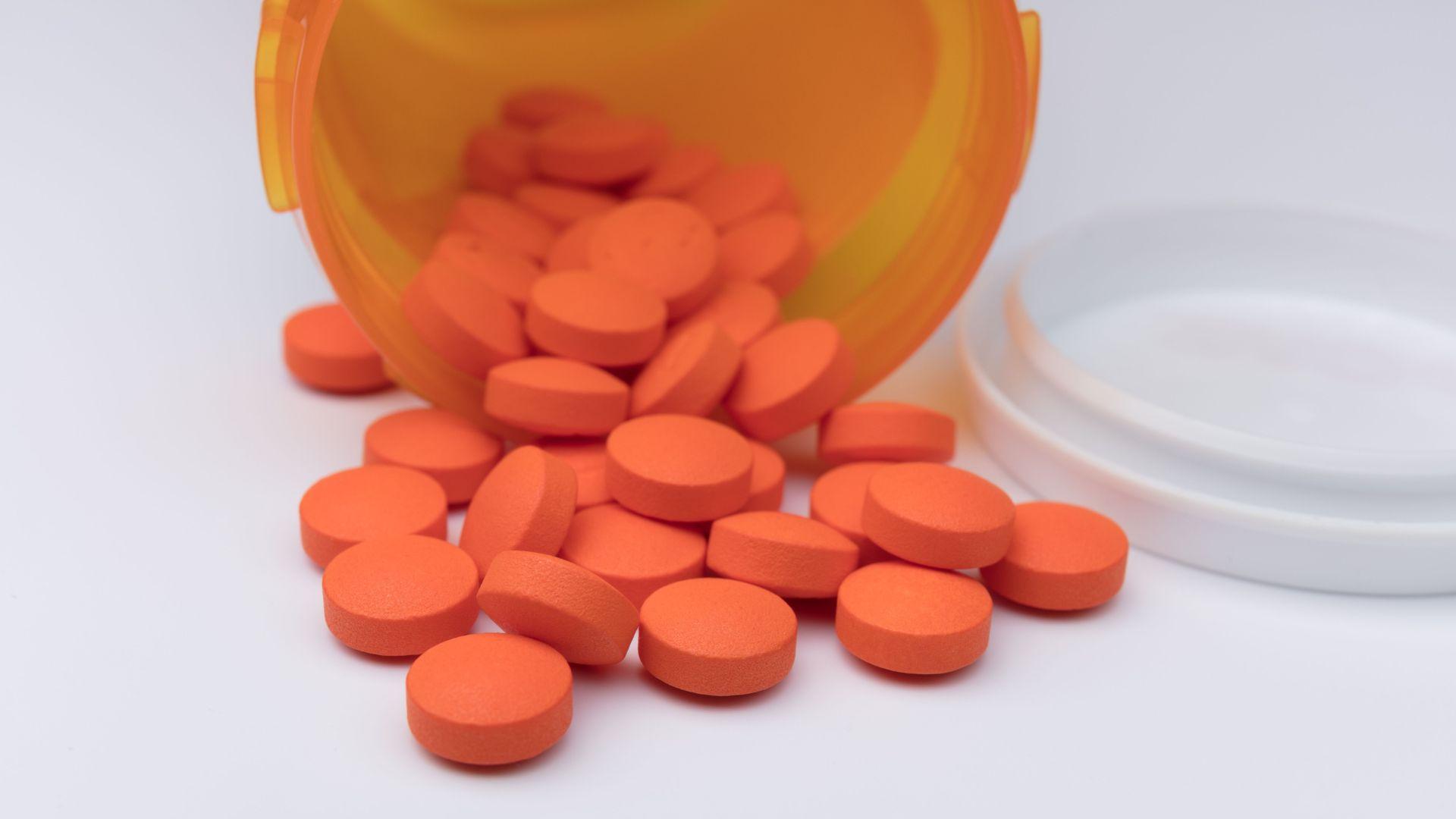Ibuprofen addiction: bottle of ibuprofen spilled showing pile of ibuprofen pills.