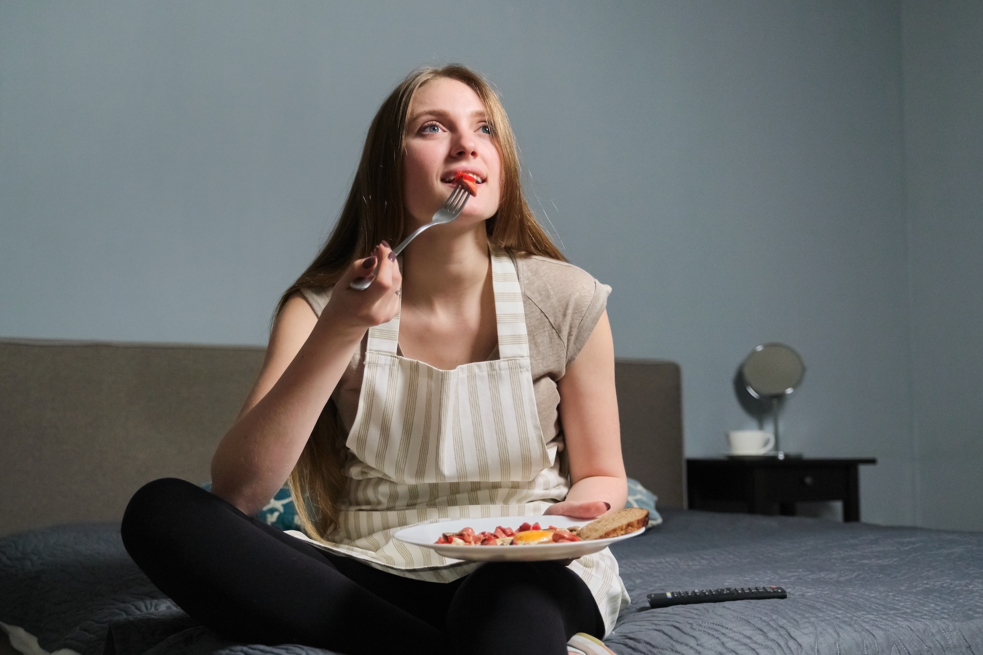 girl-sitting-on-bed-with-remote-control-watching-t-2024-12-08-03-08-14-utc