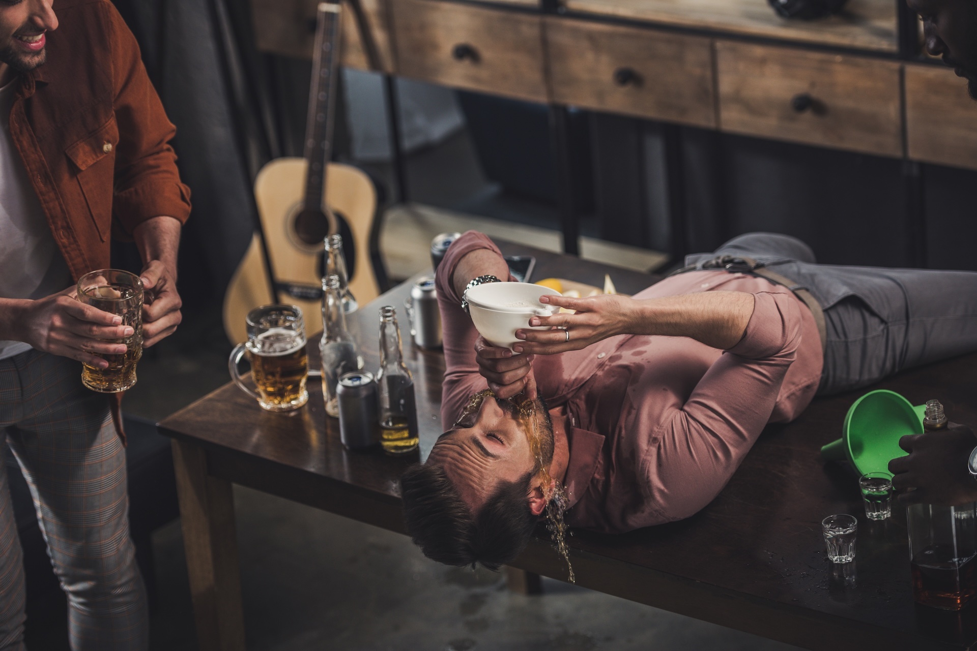 young-man-lying-on-table-and-drinking-beer-from-fu-2024-11-18-21-48-46-utc